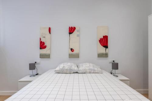 a white bedroom with a bed with red paintings on the wall at Gran apto a 5 min de casco viejo. Familias, grupos in Bilbao