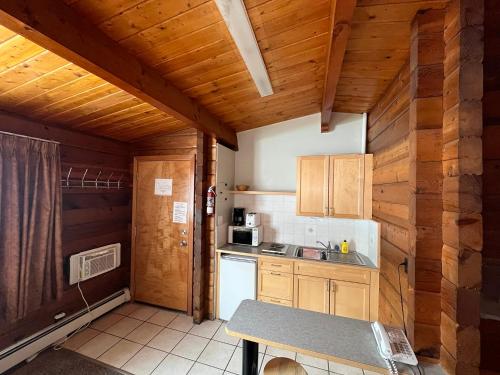 a kitchen with wooden walls and a table in a room at Raccoon Lodge Motel in Sylvan Lake