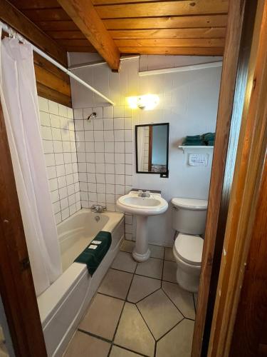 a bathroom with a toilet and a tub and a sink at Raccoon Lodge Motel in Sylvan Lake