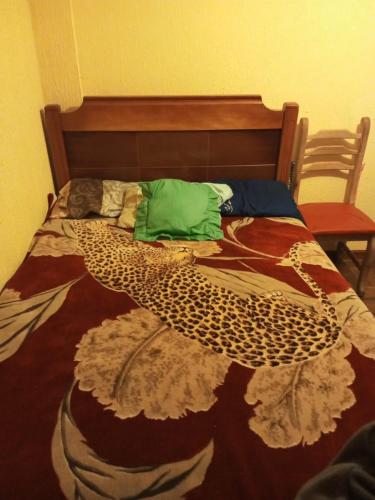 Un dormitorio con una cama con una gran colcha de pavo real en El Hogar de Jhonny, en Quito