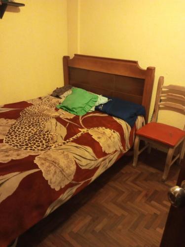 Cama en habitación con silla roja y cama sidx sidx en El Hogar de Jhonny, en Quito