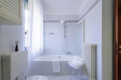 een witte badkamer met een bad en een douche bij Revo Apartments - Quadrifoglio in Sondrio