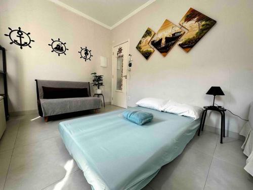 a bedroom with a large bed and a couch at Kitnet - São Vicente - Itararé in São Vicente