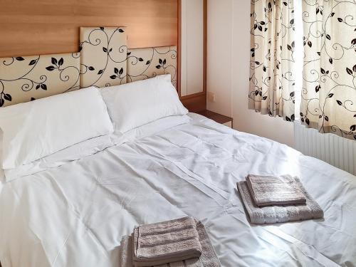 a white bed with two towels on top of it at Inglenook Lodge in Lamplugh