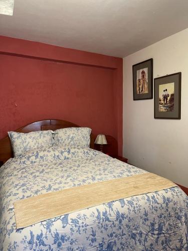 a bedroom with a bed and a red wall at Conectada al Centro Historico de Huamanga in Ayacucho