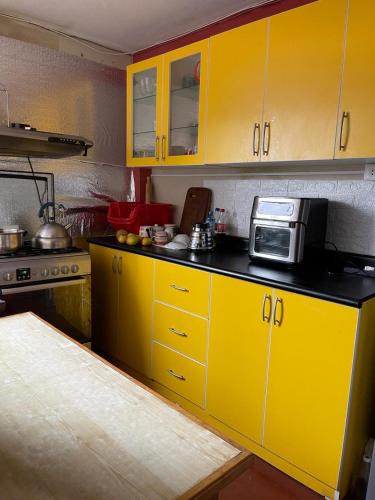 a kitchen with yellow cabinets and a microwave at Conectada al Centro Historico de Huamanga in Ayacucho