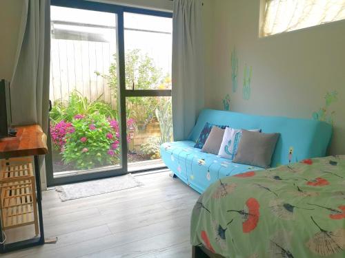 a bedroom with a blue bed and a sliding glass door at W&M Orchid House in Auckland