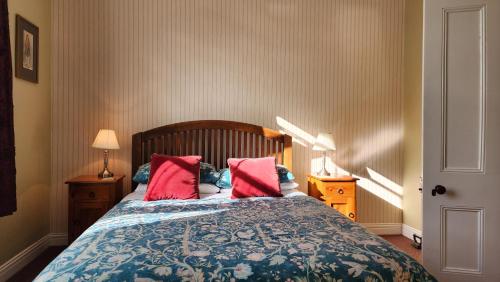 a bedroom with a bed with two red pillows at Poripori Homestead in Tauranga