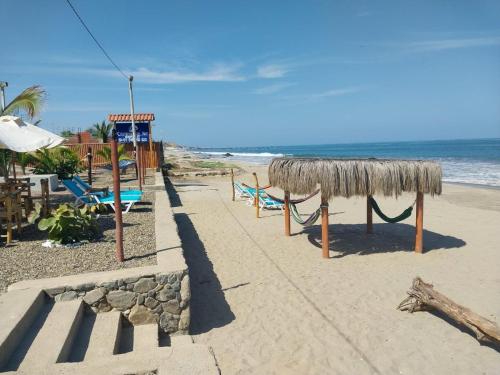 a beach with a bench and a thatch roof at Casuarinas del Mar Habitacion Cerro 2 in Canoas De Punta Sal
