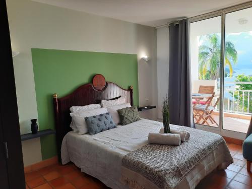 a bedroom with a bed with a green wall at ti punch vue sur mer in La Trinité