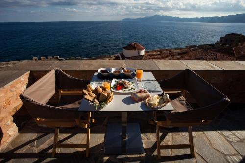 a table with food on it with the ocean in the background at House in the Castle in Monemvasia