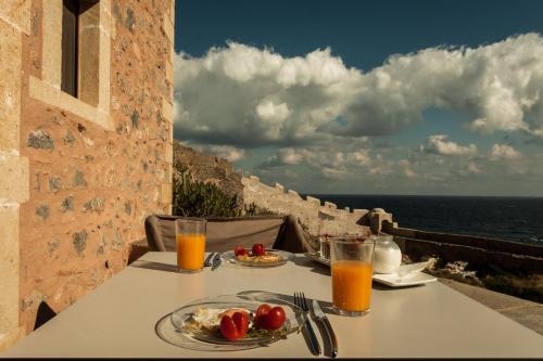 a table with plates of food and orange juice at House in the Castle in Monemvasia