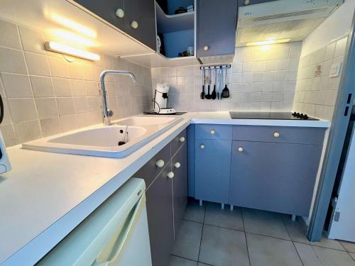 - une cuisine blanche et bleue avec un évier dans l'établissement Appartement 2 pièces avec terrasse, à 150m des plages - Cavalaire-sur-Mer - FR-1-226B-192, à Cavalaire-sur-Mer