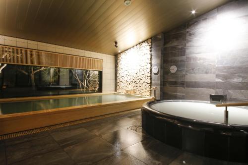 a bathroom with a bath tub and a bath tub at Nemu Resort Hotel Nemu in Shima