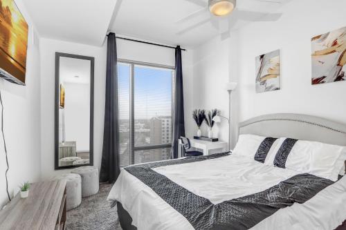 a white bedroom with a bed and a large window at Downtown Tampa Gem 1-BD w/Pool, Gym, & Sky Lounge in Tampa