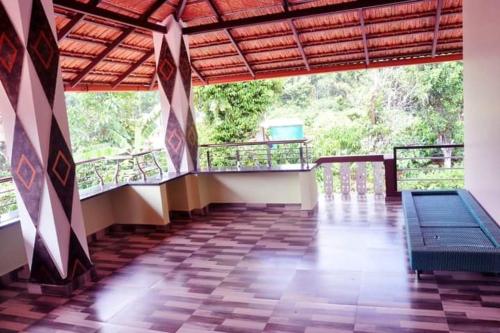 an empty room with a bench and a balcony at butterfly coorg homestay in Virajpet