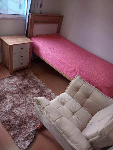 ein Wohnzimmer mit einem Sofa und einem rosa Bett in der Unterkunft AP do Brian in São João del Rei