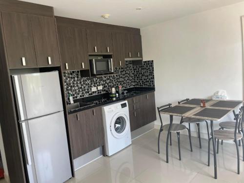 a kitchen with a washing machine and a table with chairs at Bangsaray Beach Resort in Bang Sare