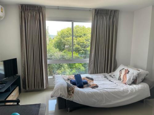 een vrouw op een bed in een slaapkamer met een raam bij Bangsaray Beach Resort in Bang Sare