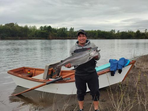 a man is holding a fish in a boat at Cisnes del tolten in Freire