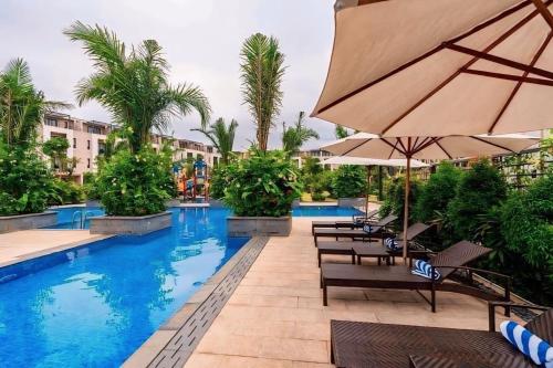a pool at a hotel with chairs and an umbrella at Royal Lotus Homestay Villa 5 Phòng Ngủ in Ha Long