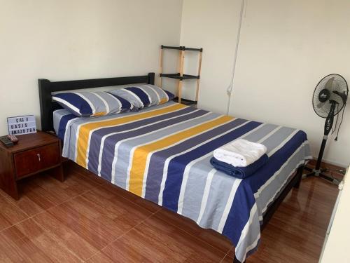 een slaapkamer met een bed met gestreepte lakens en een ventilator bij Casa Oasis in Leticia