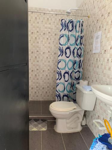 a bathroom with a toilet and a shower curtain at Casa Oasis in Leticia