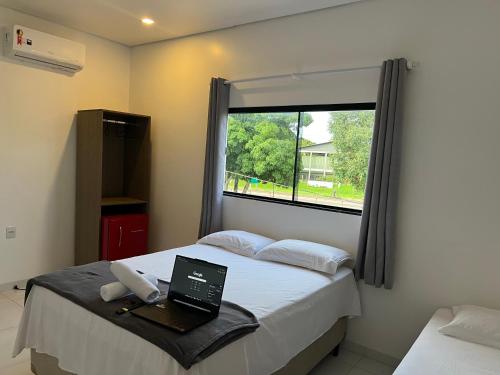 a bedroom with a laptop on a bed with a window at Cubo Hotel in Rio Branco