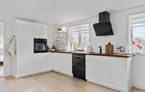 a kitchen with white cabinets and black appliances at Gorgeous Home In Melby With Wifi in Melby