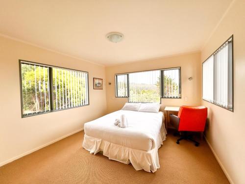 Tutukaka Dive Lodge في توتوكاكا: غرفة نوم بسرير وكرسي احمر