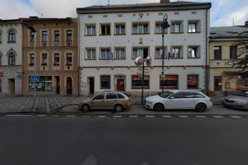 two cars parked in a parking lot in front of a building at Ubytování in Karlovy Vary