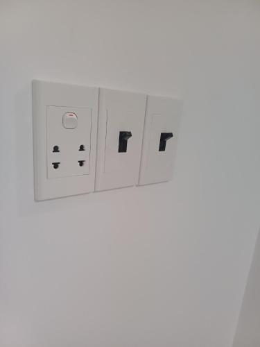 a row of white electrical switches on a wall at Maria Hotel in Ba Tri