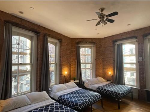 2 bedden in een kamer met ramen en een plafondventilator bij Midtown Nest Loft Studio in New York
