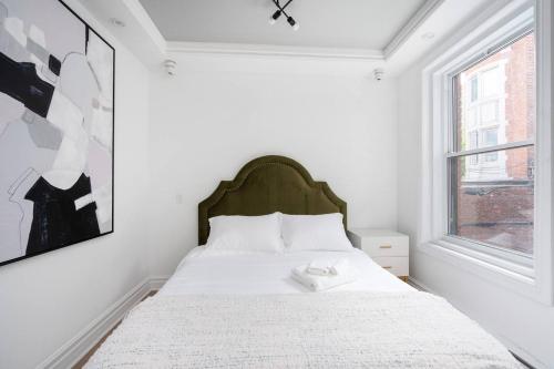 a white bedroom with a bed with a large window at Penfield Suites in Montreal