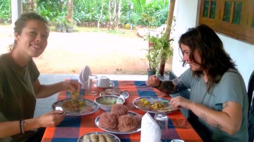 dos mujeres sentadas en una mesa comiendo comida en Sinharaja Greenvilla Homestay, en Mederipitiya