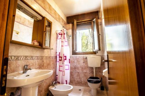 a bathroom with a sink and a toilet and a window at Ferienhaus in Lido Di Volano mit Terrasse, Grill und Garten in Lido di Volano