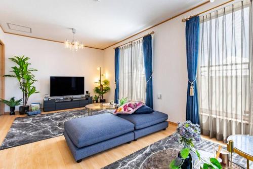 a living room with a blue couch and a tv at 【4LDKの一軒家貸し切り！】スタイリッシュで落ち着いたインテリアのハウスで沖縄を満喫しましょう！ in Jima