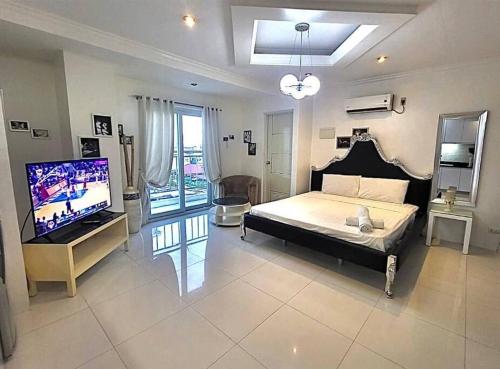 a bedroom with a bed and a flat screen tv at Sheryll Escapes - Kandi big studio l balcony l housekeeping l Netflix in Angeles