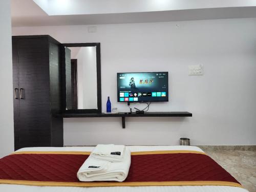 una camera con letto e TV a schermo piatto a parete di Royal Residency a Rāmanagaram