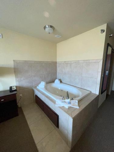 a bathroom with a bath tub with a sink at AmeriVu inn and Suites - Crookston in Crookston