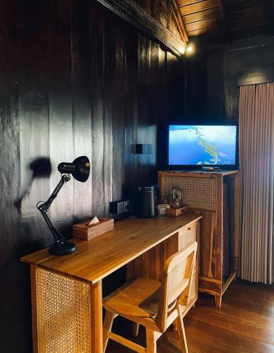 a desk with a lamp and a television in a room at Queen Rain VIla in Nusa Lembongan