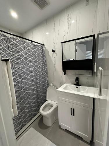 a white bathroom with a toilet and a sink at LYZ Miami Airport in Miami
