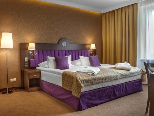 een hotelkamer met een groot bed met paarse accenten bij GRAND HOTEL Kielce in Kielce