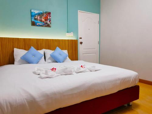 um quarto com uma cama branca e almofadas azuis em Fall Asleep hotel em Nonthaburi