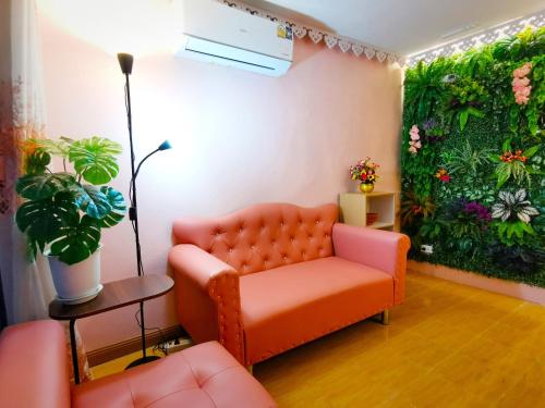 a living room with an orange couch and a green wall at Fall Asleep hotel in Nonthaburi