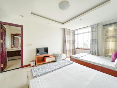 a bedroom with two beds and a tv and a mirror at Sunny Motel Tuần Châu in Ha Long