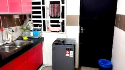 a small kitchen with red cabinets and a refrigerator at Homestay Hafiy Manjung Lekir Sitiawan in Lekir