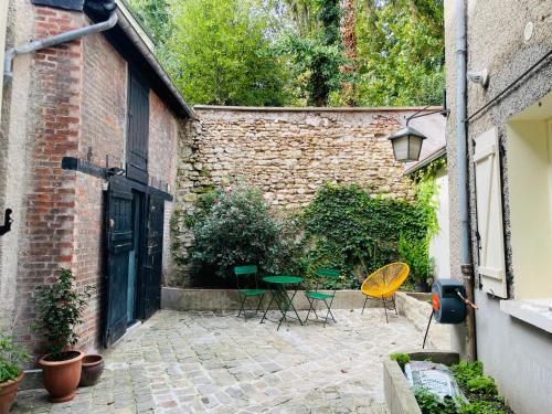 a courtyard with chairs and a table and a building at Maisonette duplex - Tout equipé - Matelas haute qualité in Marly-le-Roi