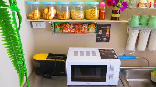 a microwave sitting on a counter next to a sink at Fall Asleep hotel in Nonthaburi
