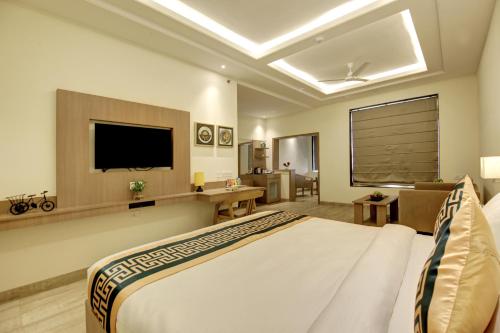 ニューデリーにあるHotel AMBS suites A family Hotel Near Delhi Airportのベッドとテレビが備わるホテルルームです。